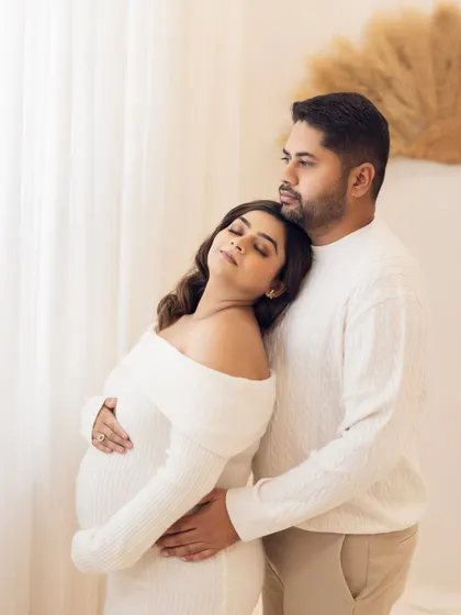 A moment of peaceful reflection. The mother-to-be leans her head on her partner's shoulder with her eyes closed, conveying a sense of trust and serenity during their maternity session.
