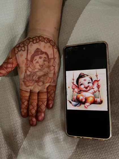 This image shows the reference photo next to my henna recreation of a baby Ganesha, demonstrating my ability to accurately replicate images in my art.