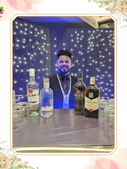 A smiling bartender behind a bar lit by twinkling fairy lights. This image conveys a sense of warmth and celebration.