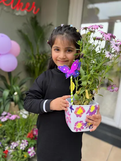 The finished product! This happy guest is showing off her beautifully painted planter and a butterfly wand she crafted. Every child leaves our parties with their own handmade treasures.