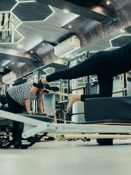 This wide-angle shot captures the focus of a group class performing a challenging plank variation. Each client is engaged, using the Reformer to build core strength and endurance.