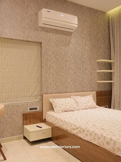 This bedroom features a textured grey wallpaper and a simple wooden bed frame. The built-in desk and shelving provide a dedicated workspace without cluttering the room.