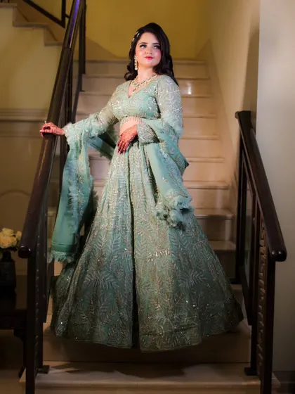 A stunning full-length shot of the bride on the stairs, showcasing the beautiful flow and intricate details of her lehenga.