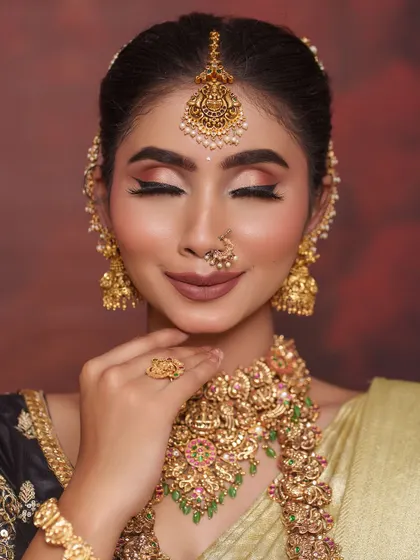 This close-up highlights the flawless makeup and the intricate details of the temple jewelry, including the beautiful maang tikka and nose ring.