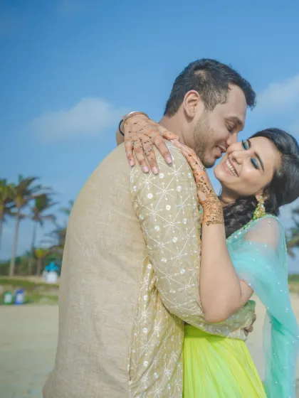 A close-up of the couple sharing an affectionate hug on the beach. The genuine smiles and sunny backdrop make this a heartwarming and candid shot.