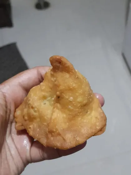 A perfectly fried, golden-brown samosa. It's crispy on the outside and filled with a savory, flavorful stuffing.