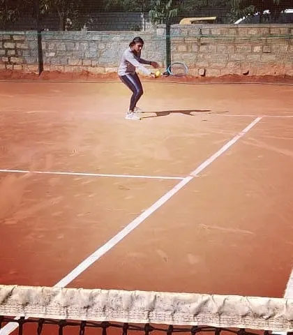 A female player hitting a low backhand during a match at the Open Tournament.