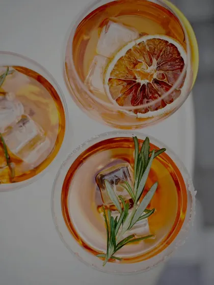 An overhead shot of artisanal cocktails garnished with dehydrated orange and fresh rosemary.