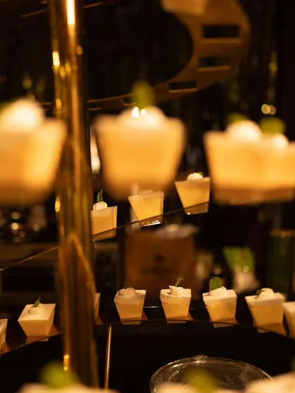 A display of mini dessert cups on an elegant, spiraling gold stand.