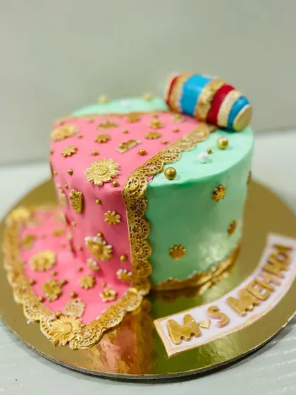 A beautiful and unique cake for a Mehndi night, designed to look like a traditional outfit with intricate gold piping and a dholak.