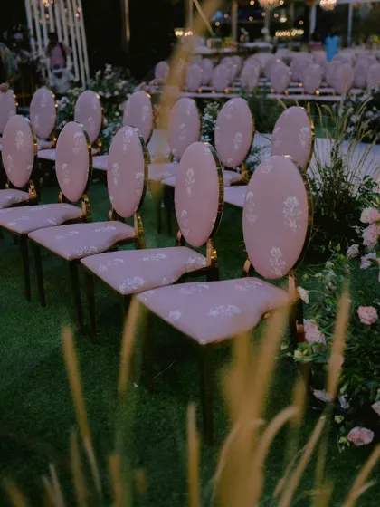 Custom-designed chairs with elegant pink upholstery, created specifically for Nidhi and Amit's ceremony. The floral motif on the fabric tied in perfectly with the surrounding garden installations.