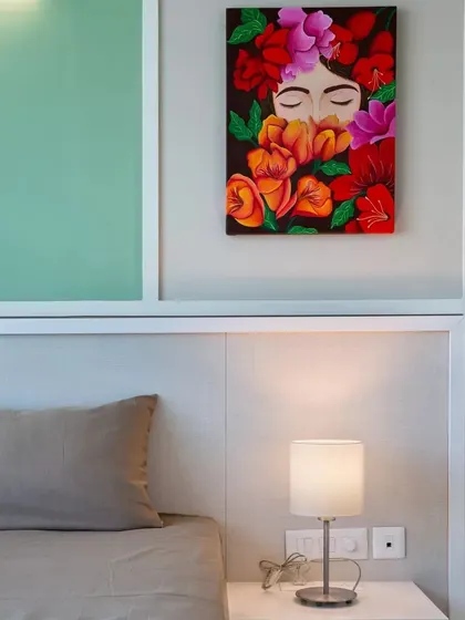 A bedroom at Conscient One where art is the essence, featuring a vibrant floral painting above the bed.