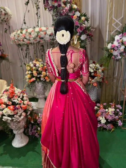 This hairstyle features a unique segmented braid, with each section neatly wrapped. A large jasmine veni at the top adds a classic touch, making it perfect for a traditional ceremony.