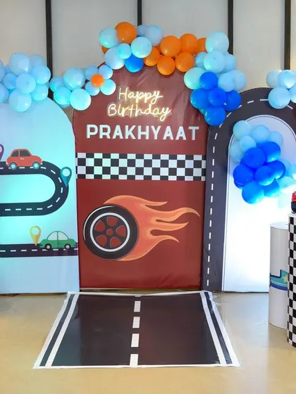 A vibrant, car-themed fifth birthday party setup, complete with a racetrack, traffic lights, and colorful balloons. We enjoy capturing the energy and creativity of themed parties for kids of all ages.