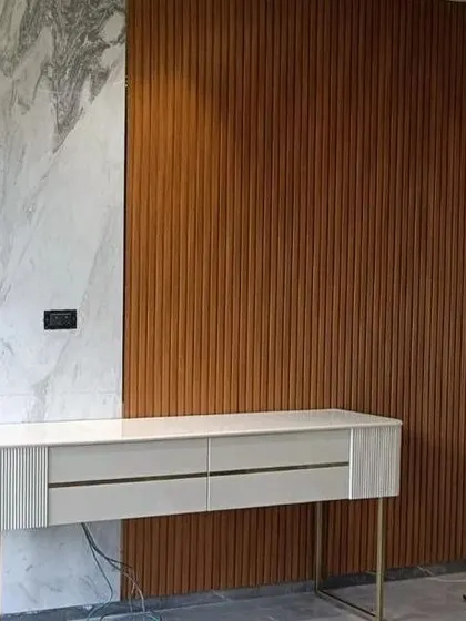 A minimalist white console table set against a backdrop of fluted wood paneling and marble. This image shows our furniture being installed on-site as part of a larger interior project.