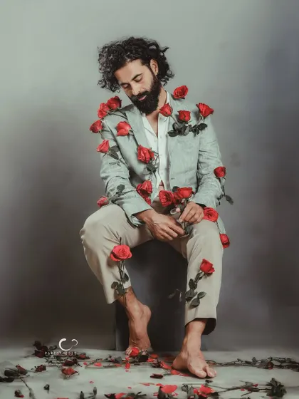 A softer moment within the rose-adorned suit concept. His gentle smile adds a layer of warmth and acceptance to the surreal imagery.