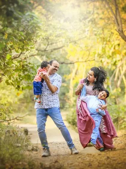 A family of four enjoys a playful moment in a sunlit forest. The image is full of movement and laughter, capturing the authentic and joyful spirit of my family sessions.