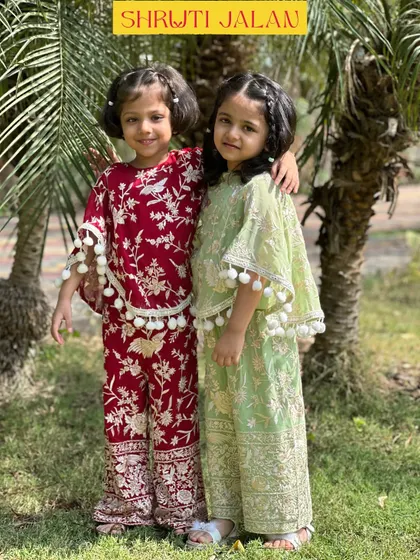 There is nothing sweeter than sisterly love, and I adore creating outfits to celebrate it. These two are wearing my coordinated sets, one in a rich maroon and the other in a soft pistachio green, both featuring playful pom-pom details for a touch of fun.