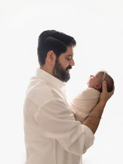 A father holds his newborn baby up, looking at her with so much love. These are the moments that become cherished memories.