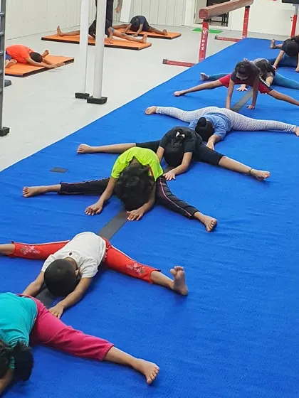 Students hold a deep straddle stretch, working on opening their hips and lengthening their hamstrings.