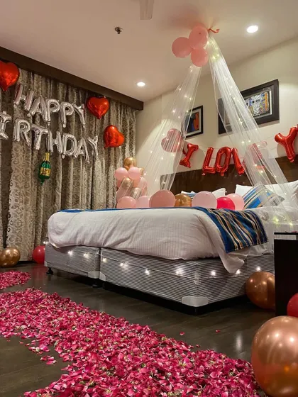 A closer view of the birthday room decor, focusing on the bed area with the light-up canopy, 'I Love You' balloons, and pink and rose-gold balloon clusters.