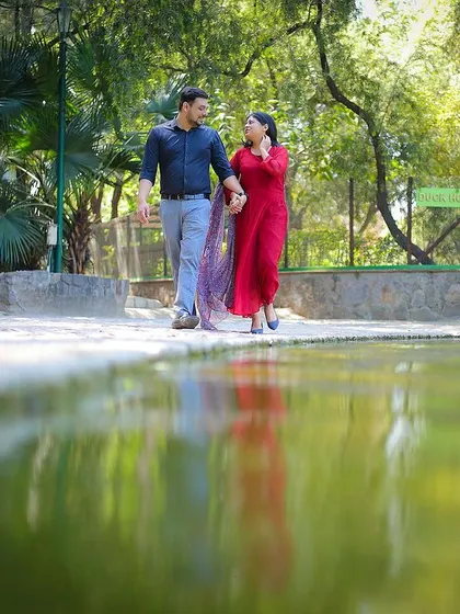 A beautiful reflection shot from a pre-wedding session by the water, capturing the couple's stroll in a picturesque park setting.