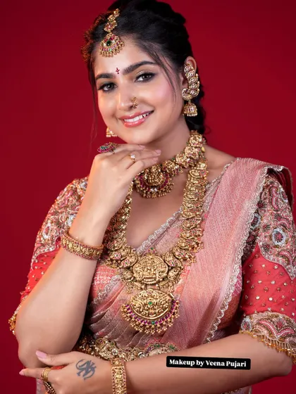 A complete traditional bridal look. The combination of a soft pink Kanjivaram saree, heavy temple jewelry, and glowing makeup creates a timeless and regal appearance for the bride.