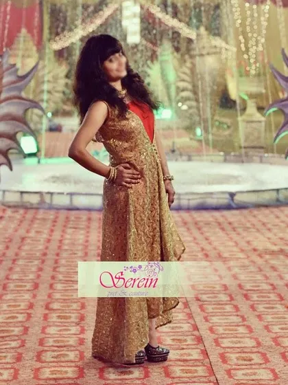 A client looking chic in a custom-designed high-low jacket paired with a jumpsuit. The golden brocade jacket adds a touch of glamour, making this a perfect Indo-western outfit for a wedding party.