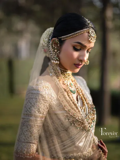 A soft, artistic shot of the bride. The dewy makeup and gentle lighting highlight the intricate details of her jewellery and the delicate fabric of her veil.
