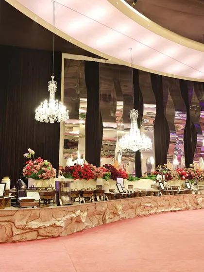 A wide shot of one of our grand buffet setups, adorned with crystal chandeliers and elaborate floral arrangements. We believe the food display should be a feast for the eyes before it even reaches the plate.