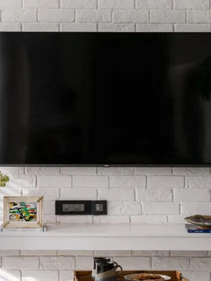 A close-up of the minimalist TV wall, featuring a clean, floating shelf against the textured white brick. This uncluttered design enhances the tranquility of the home, proving that simplicity can be incredibly stylish.
