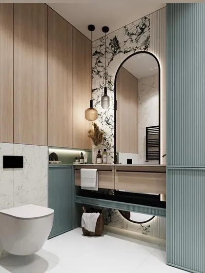 Another view of the pastel blue and marble bathroom, highlighting the ample storage provided by the floor-to-ceiling cabinets. The wall-mounted toilet and floating vanity help to make the space feel open and easy to clean.