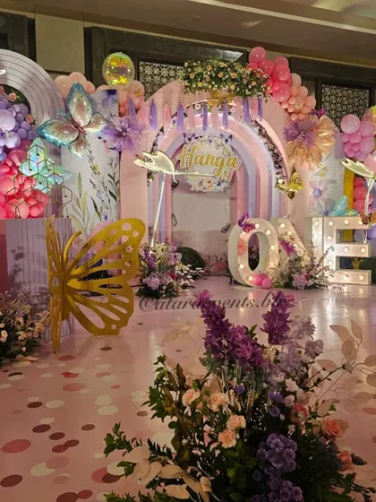A closer look at the enchanting stage for a butterfly-themed first birthday. The 'ONE' marquee lights add a beautiful glow to the pastel-colored decor, complete with floral arrangements and butterfly cutouts.