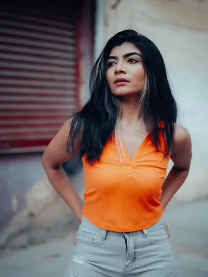 A confident and direct street portrait. The model's pose and the simple urban background create a powerful and engaging image.