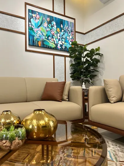 A close-up of the living room decor, featuring hammered gold vases and a terrarium on a glass coffee table. These details add a touch of luxury and personality to the space.