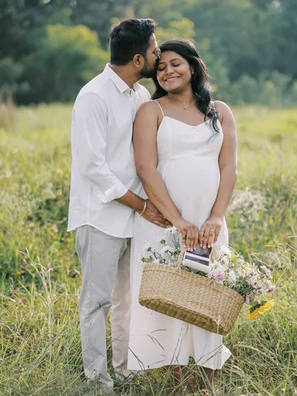 A sweet outdoor portrait incorporating a basket of flowers and their ultrasound scan. It’s a lovely way to combine romantic elements with the personal story of their pregnancy.