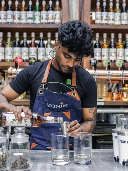 This is mixology as an art form. A bartender carefully measures ingredients for a low-ABV cocktail, using premium spirits and house-made infusions for a complex flavor profile.