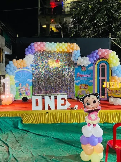Another angle of the Cocomelon birthday stage, showing the full balloon arch over the shimmer backdrop and the arrangement of character props.
