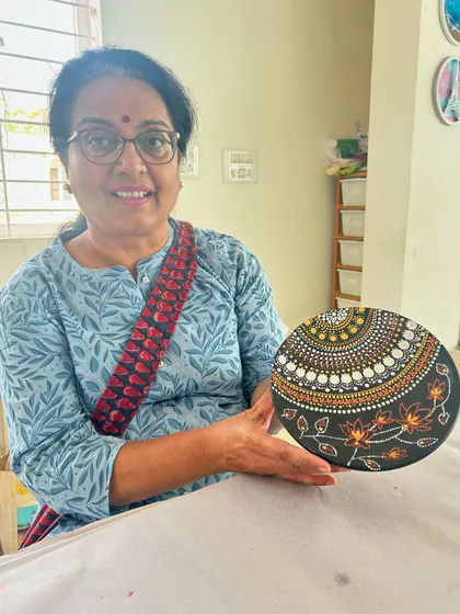 A participant displays the intricate dot mandala plate she painted.