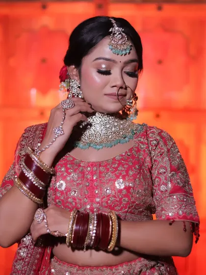 A close-up portrait focusing on the bride's delicate pose and jewellery. Her hand gently touches her elaborate choker, drawing attention to the intricate craftsmanship of her accessories.