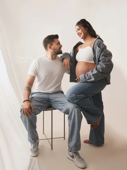 A relaxed and stylish pose. The way she leans on him with a happy smile shows their easygoing chemistry, perfect for a casual studio session.