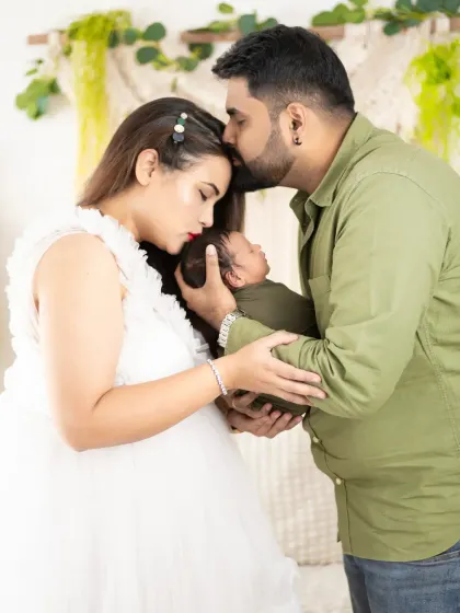 A classic family pose with a newborn. The parents' gentle kisses on the baby's head create a circle of love and protection around their newest family member.