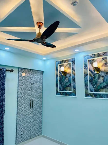 A beautiful bedroom with a geometric-patterned wardrobe and a feature wall with tropical wallpaper panels. The false ceiling design adds a touch of modern geometry.