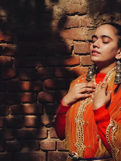 Another look from the jewelry styling project, focusing on heavy silver jhumkas paired with an embroidered orange dupatta. The play of light and shadow against the brick wall adds to the raw, authentic aesthetic.