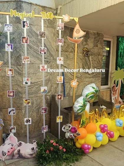 A creative photo display for a Moana-themed party. We used vertical stands decorated with themed cutouts to hang photos from the first year.