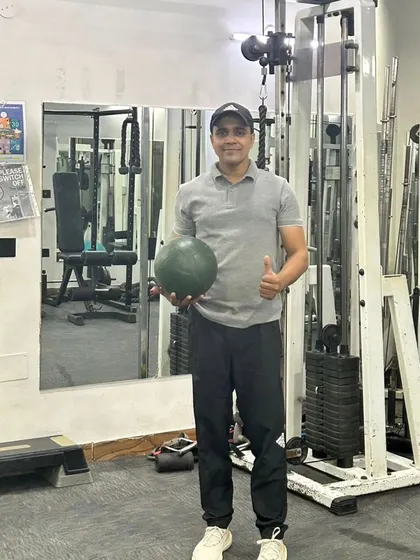 Holding a medicine ball in the gym. We use equipment like this for functional strength exercises, including core work and explosive power drills.