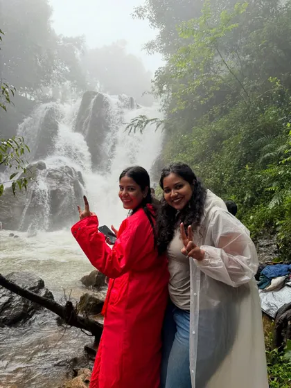 Two friends in their raincoats posing by a beautiful waterfall on the Bandaje trail. The monsoon season makes these falls even more spectacular.