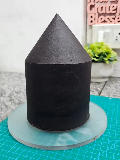 The "before" shot of the circus tent cake. This shows the basic carved shape of the cake, covered in dark chocolate ganache, before the fondant and details are applied.