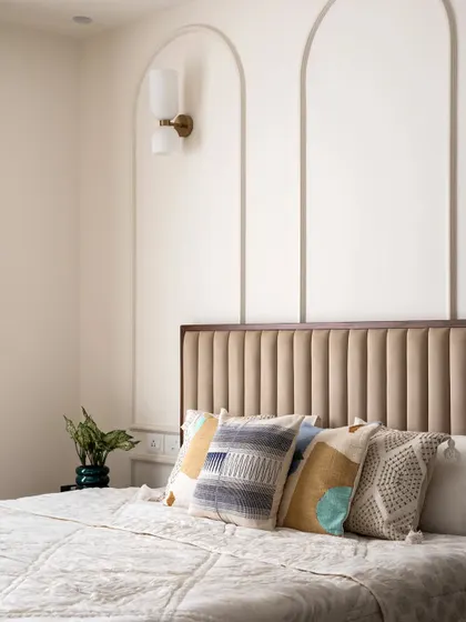 The master bedroom features a beautiful curved wall beading highlight, complemented by a scone wall light. The headboard, a combination of fabric and veneer, adds a luxurious feel.