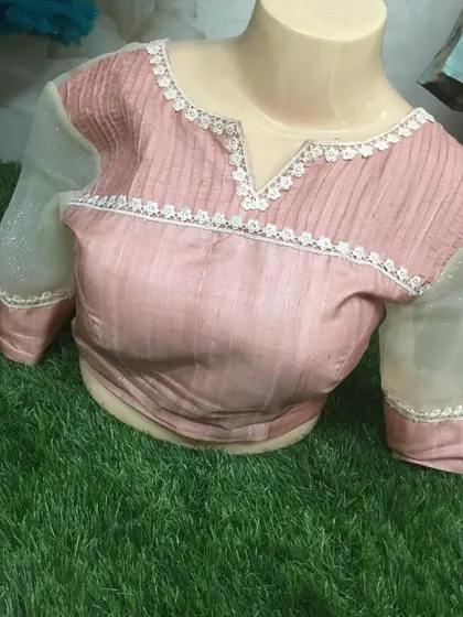 The front of the dusty pink blouse has a simple neckline with lace details.